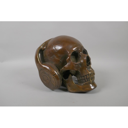 226 - A decorative filled bronze skull wearing headphones, 17cm high