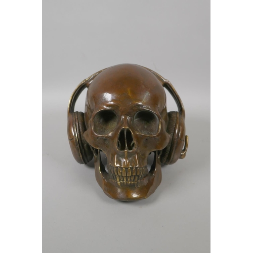 226 - A decorative filled bronze skull wearing headphones, 17cm high