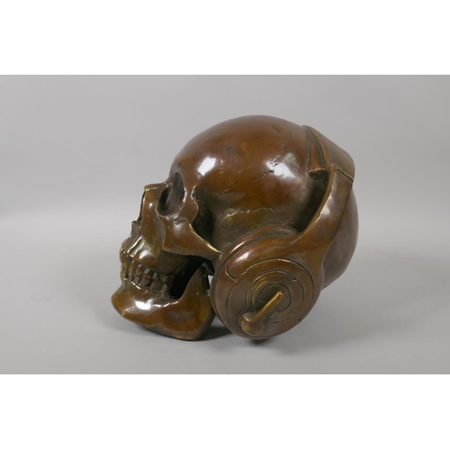 226 - A decorative filled bronze skull wearing headphones, 17cm high