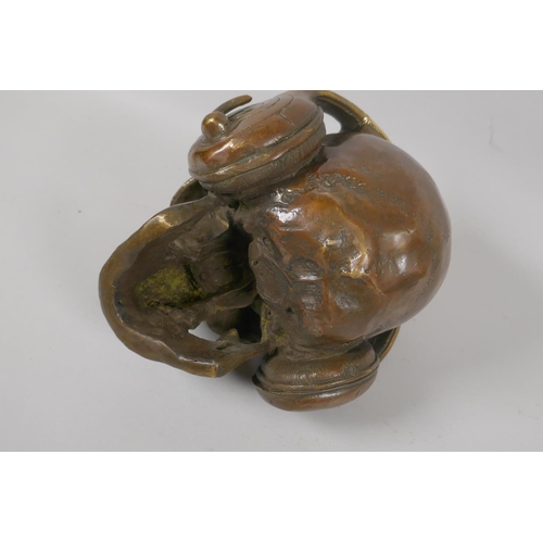 226 - A decorative filled bronze skull wearing headphones, 17cm high