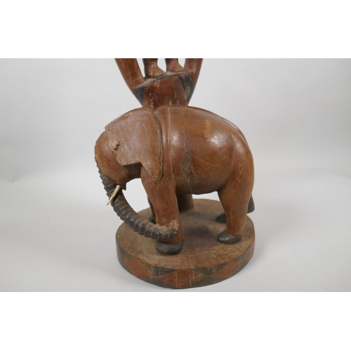 229 - An African carved hardwood lamp base in the form of a figure in a tree and an elephant, 52cm high