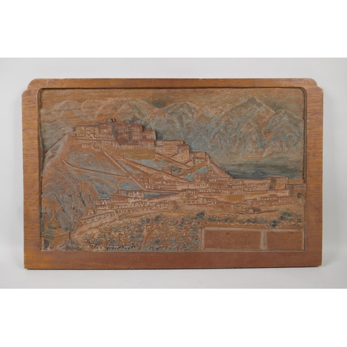 25 - A C19th Tibetan carved teak panel depicting The Potala at Lhasa, the lower right carved with an insc... 