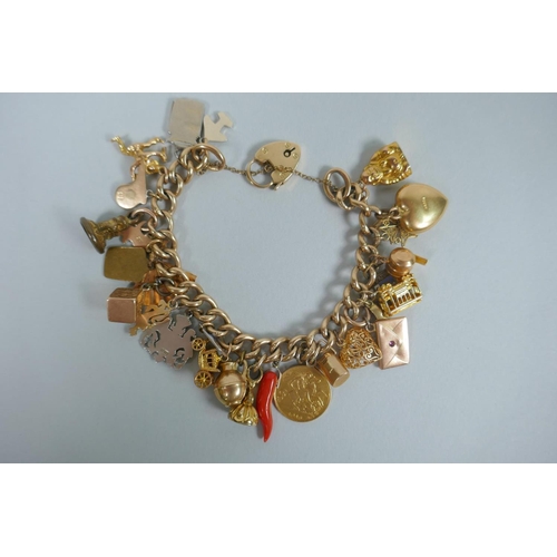 605 - A 9ct gold charm bracelet with numerous 9ct, 14ct, 18ct and 22ct gold charms, and a few yellow metal... 