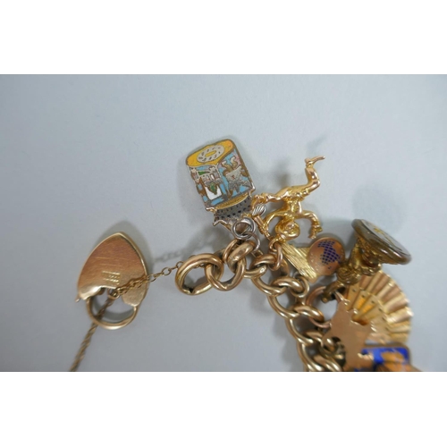 605 - A 9ct gold charm bracelet with numerous 9ct, 14ct, 18ct and 22ct gold charms, and a few yellow metal... 