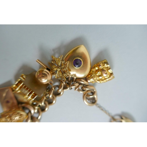 605 - A 9ct gold charm bracelet with numerous 9ct, 14ct, 18ct and 22ct gold charms, and a few yellow metal... 