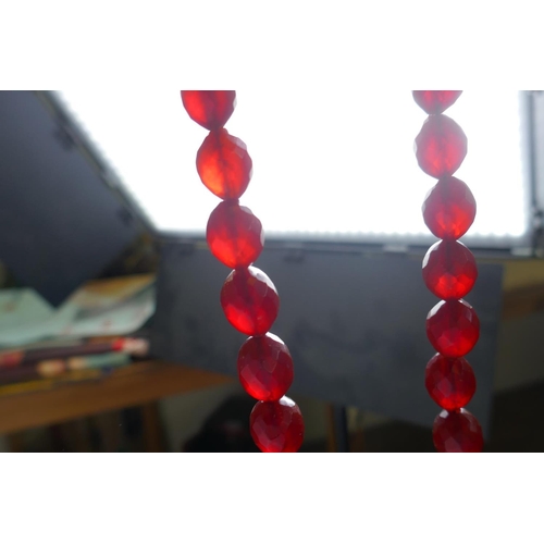 620 - A string of faceted and graduated cherry amber beads, 64g, 68cm, and a Baltic amber graduated bead n... 