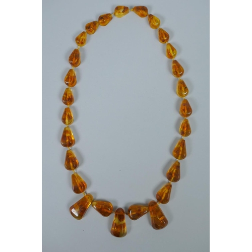 620 - A string of faceted and graduated cherry amber beads, 64g, 68cm, and a Baltic amber graduated bead n... 