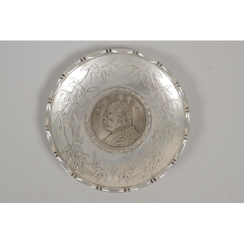 630 - A Chinese white metal coin dish with raised lotus flower decoration, and another similar with bamboo... 