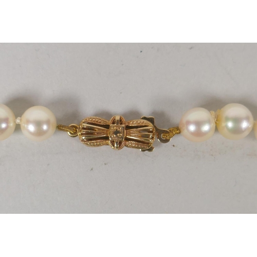 634 - A vintage pearl necklace with a 9ct gold bow shaped clasp, 42cm long