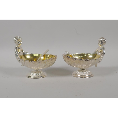 645 - A pair of silver plated clam shaped salts with putti decoration, 10cm high