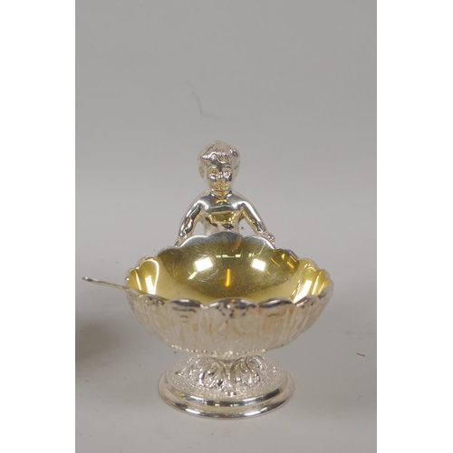 645 - A pair of silver plated clam shaped salts with putti decoration, 10cm high