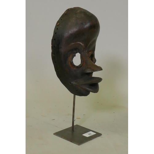 89 - African painted and carved wood tribal mask, Dan tribe, Ivory Coast, on a metal stand, 37cm