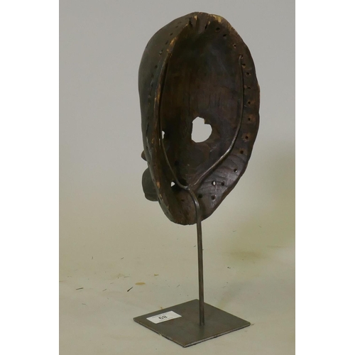 89 - African painted and carved wood tribal mask, Dan tribe, Ivory Coast, on a metal stand, 37cm