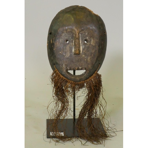 91 - African tribal mask, stained wood with grass beard, Lega tribe, Congo, mounted on a metal stand, 37c... 