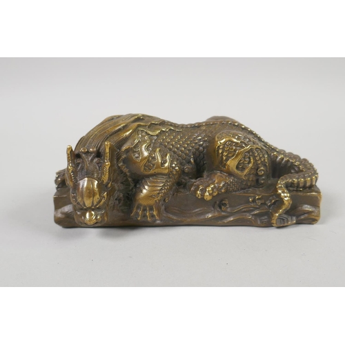 96 - A Chinese filled bronze figure of a slumbering kylin, impressed mark to base, 14cm x 6cm