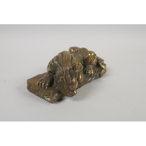 96 - A Chinese filled bronze figure of a slumbering kylin, impressed mark to base, 14cm x 6cm