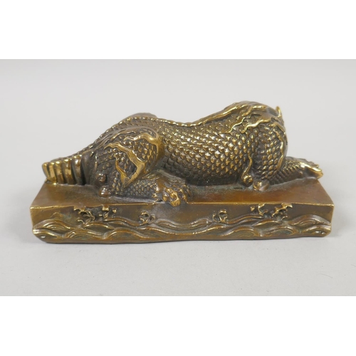 96 - A Chinese filled bronze figure of a slumbering kylin, impressed mark to base, 14cm x 6cm