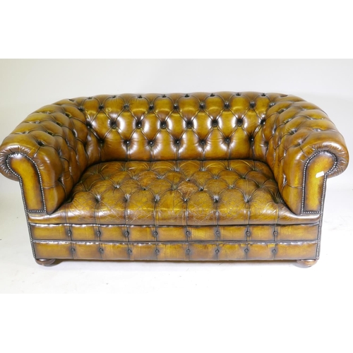 1003 - A leather chesterfield with button back and seat, and studded decoration, raised on bun feet, 177cm ... 