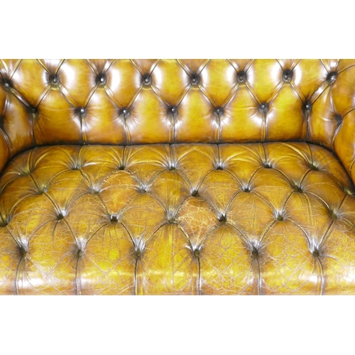 1003 - A leather chesterfield with button back and seat, and studded decoration, raised on bun feet, 177cm ... 