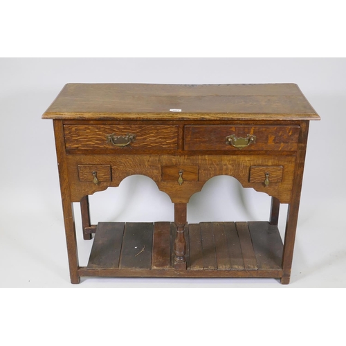 1013 - An oak side table with two long and three short drawers, and shaped apron with planked undertier, 92... 