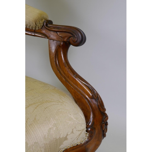 1033 - A Victorian faded rosewood open arm easy chair with carved decoration and serpentine shaped front, r... 