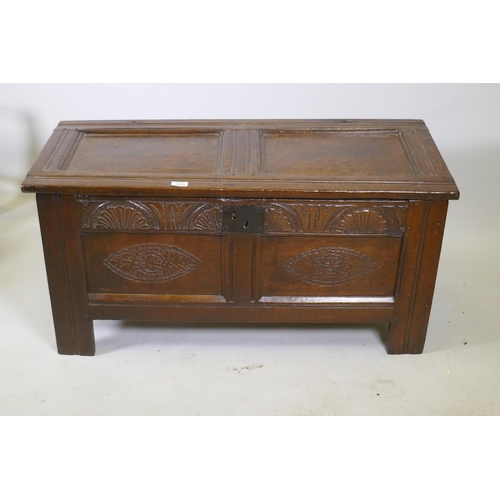 1035 - An C18th oak two panel coffer with hinged top, carved frieze and front panels, raised on stile suppo... 