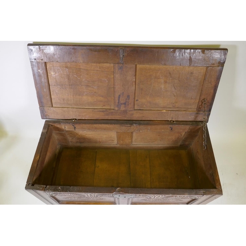 1035 - An C18th oak two panel coffer with hinged top, carved frieze and front panels, raised on stile suppo... 