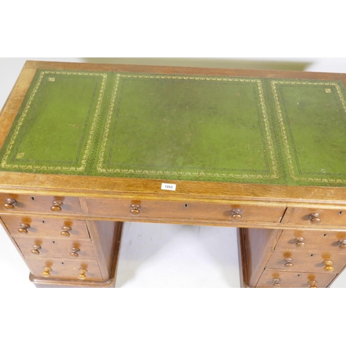 1052 - Victorian oak veneered nine drawer pedestal desk with gilt tooled leather inset top, 122 x 60 x 72cm