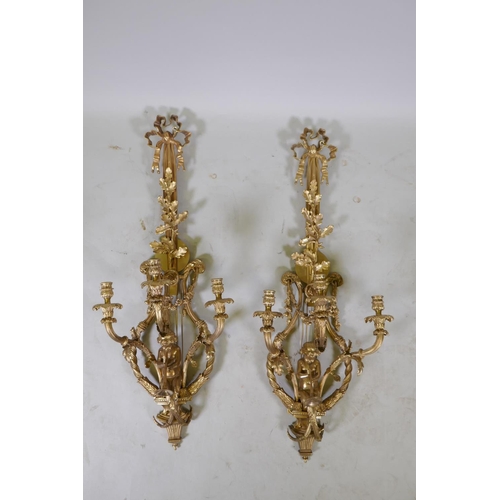 1056 - A pair of ormolu three branch Rococo style wall sconces with putti, oak leaf and swag decoration, 98... 