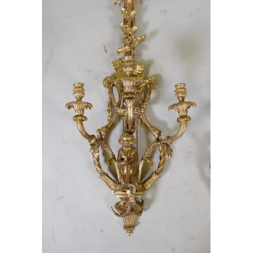 1056 - A pair of ormolu three branch Rococo style wall sconces with putti, oak leaf and swag decoration, 98... 