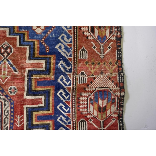 1060 - An antique Persian red ground wool Yalameh rug with a blue medallion design, 118 x 255cm