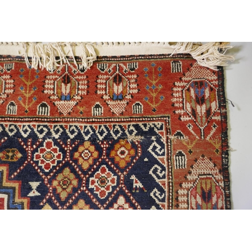 1060 - An antique Persian red ground wool Yalameh rug with a blue medallion design, 118 x 255cm