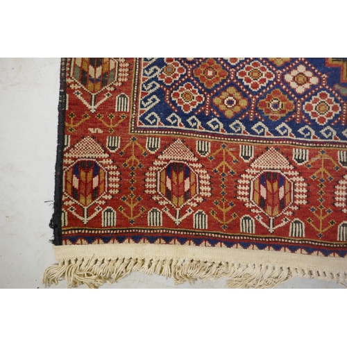 1060 - An antique Persian red ground wool Yalameh rug with a blue medallion design, 118 x 255cm