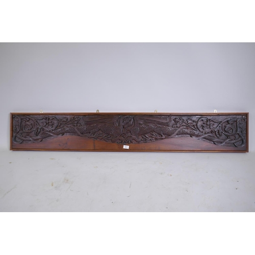 1077 - An Arts & Crafts style teak panel carved with winged dragons and foliate designs, in a mahogany ... 