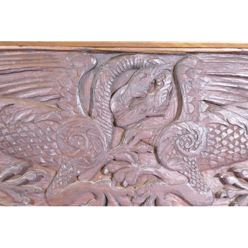 1077 - An Arts & Crafts style teak panel carved with winged dragons and foliate designs, in a mahogany ... 