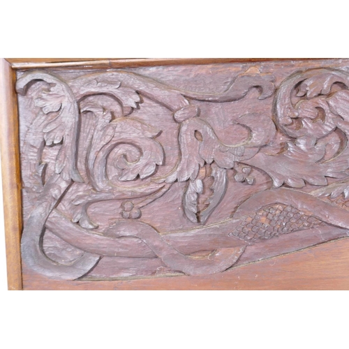 1077 - An Arts & Crafts style teak panel carved with winged dragons and foliate designs, in a mahogany ... 