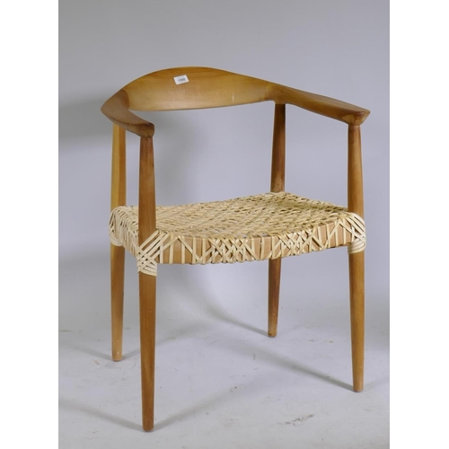 1080 - A Scandinavian style beechwood armchair with leather strapped seat after Hans Wegner