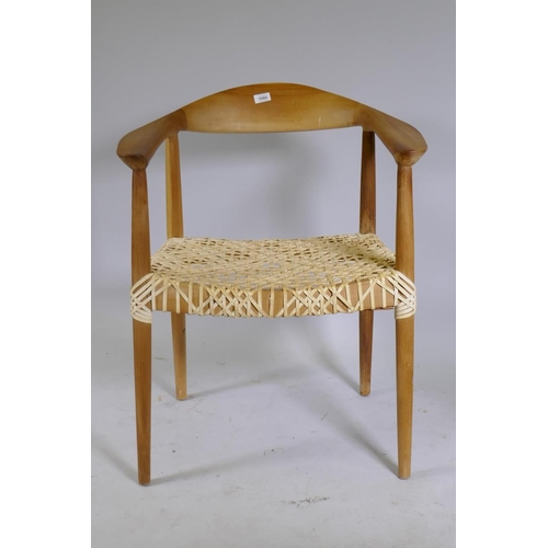 1080 - A Scandinavian style beechwood armchair with leather strapped seat after Hans Wegner