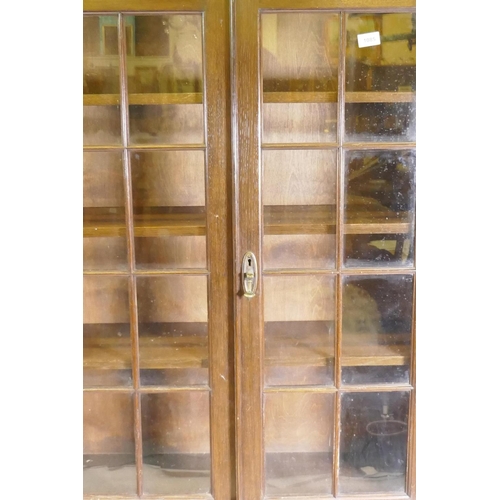 1085 - An oak bookcase, the upper section with two glazed doors, the lower two cupboards with moulded decor... 