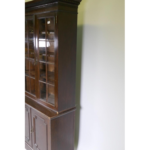 1085 - An oak bookcase, the upper section with two glazed doors, the lower two cupboards with moulded decor... 