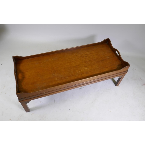 1089 - A mahogany tray top occasional table raised on square chamfered supports, 124 x 52 x 42cm