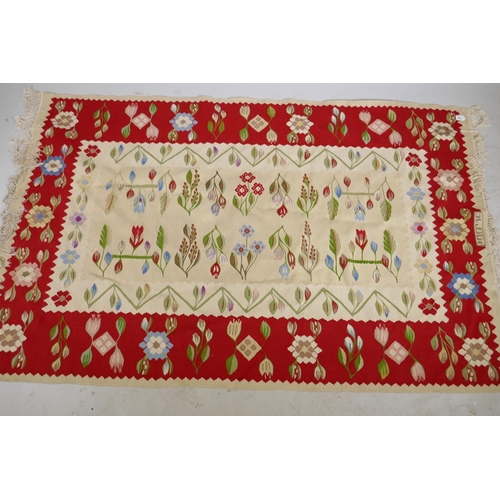 1100 - A vintage kilim rug with floral designs and a red border, signed, 195 x 122cm