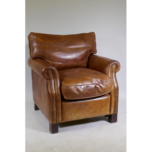 1101 - A leather club chair with brass stud detail, raised on block supports