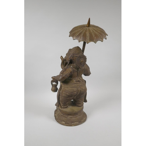 12 - An antique Indian bronze figure of Ganesh carrying a parasol, 41cm high