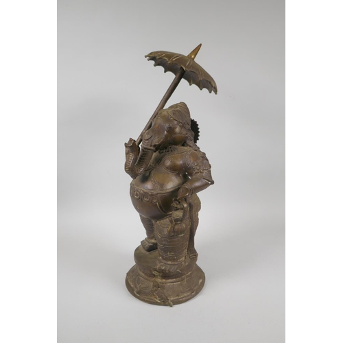 12 - An antique Indian bronze figure of Ganesh carrying a parasol, 41cm high