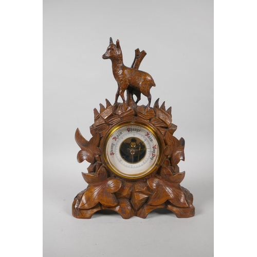 120 - A brass barometer in a carved Black Forest mount, decorated with a deer and leaves, 29cm high