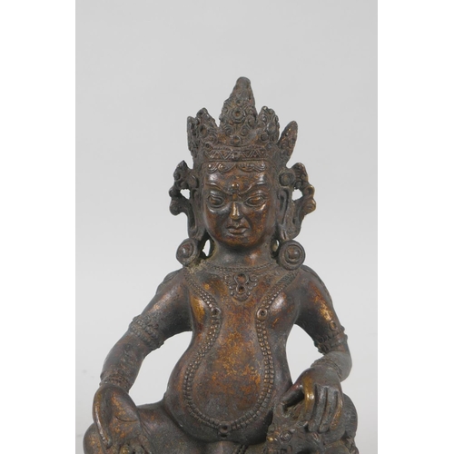 121 - A Tibetan bronzed metal figure of Jambhala, with the remnants of gilt patina, 18cm high