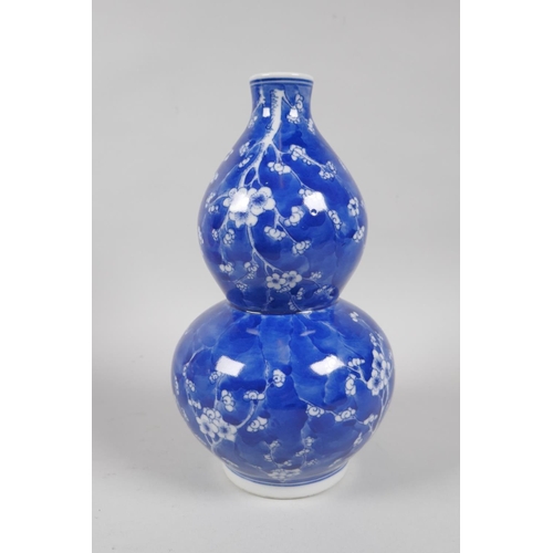 131 - A Chinese blue and white porcelain double gourd vase decorated with prunus blossom on a cracked ice ... 