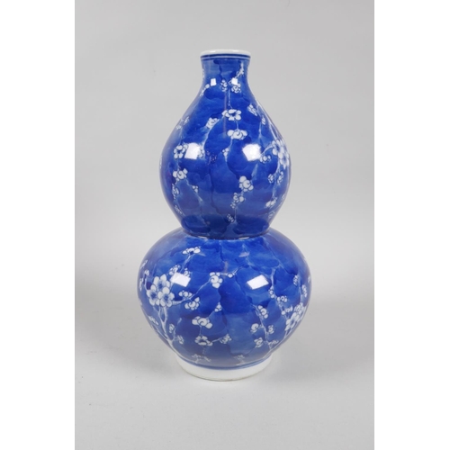 131 - A Chinese blue and white porcelain double gourd vase decorated with prunus blossom on a cracked ice ... 