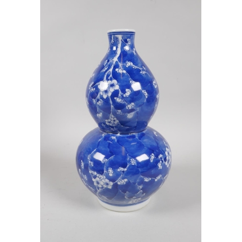 131 - A Chinese blue and white porcelain double gourd vase decorated with prunus blossom on a cracked ice ... 